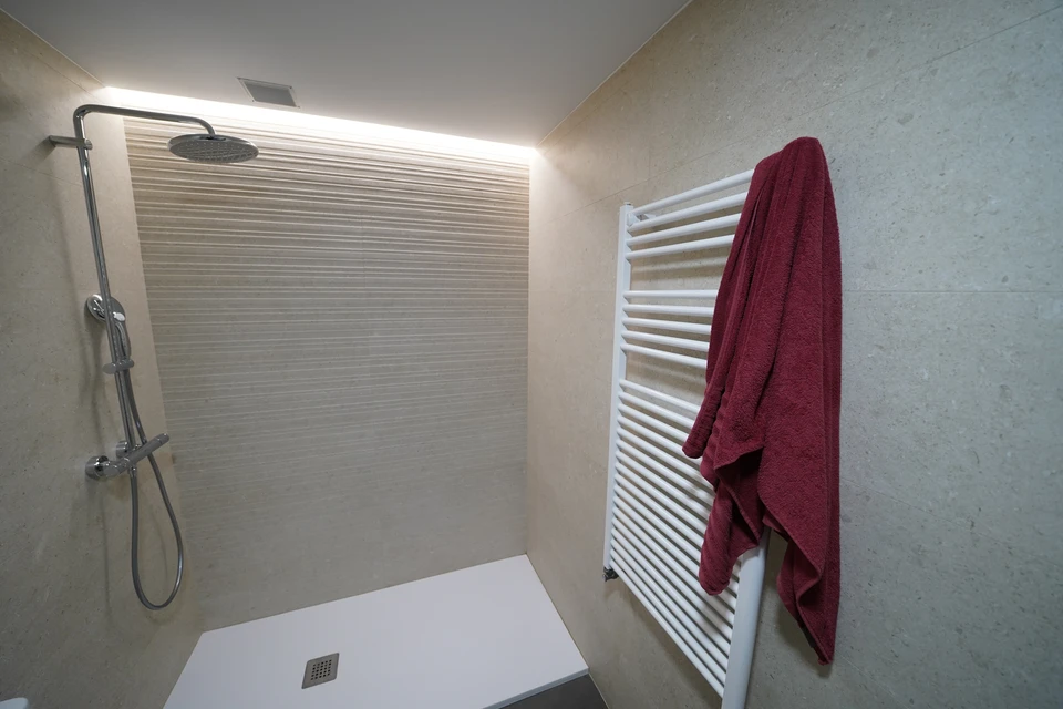 Artisan carreleur agenouillé sur un chantier intérieur appliquant du mortier-colle sur carrelage avec une truelle