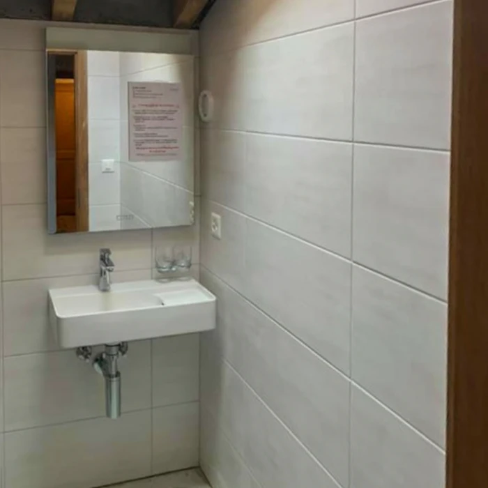 Salle de bain moderne avec meuble vasque suspendu noir à tiroirs, plan vasque rectangulaire bleu lumineux LED intégré