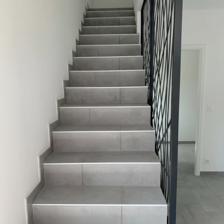 Salle de bain moderne avec douche à l'italienne vitrée, meuble vasque suspendu en bois clair à lamelles verticales, plan de toilette blanc intégré