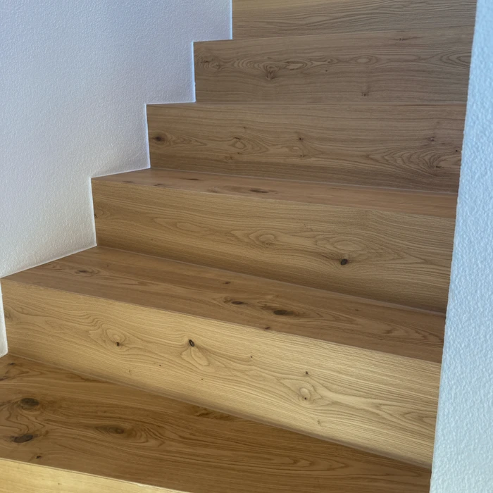 Salle de bain moderne avec douche à l'italienne vitrée, meuble vasque suspendu en bois clair à lamelles verticales, plan de toilette blanc intégré