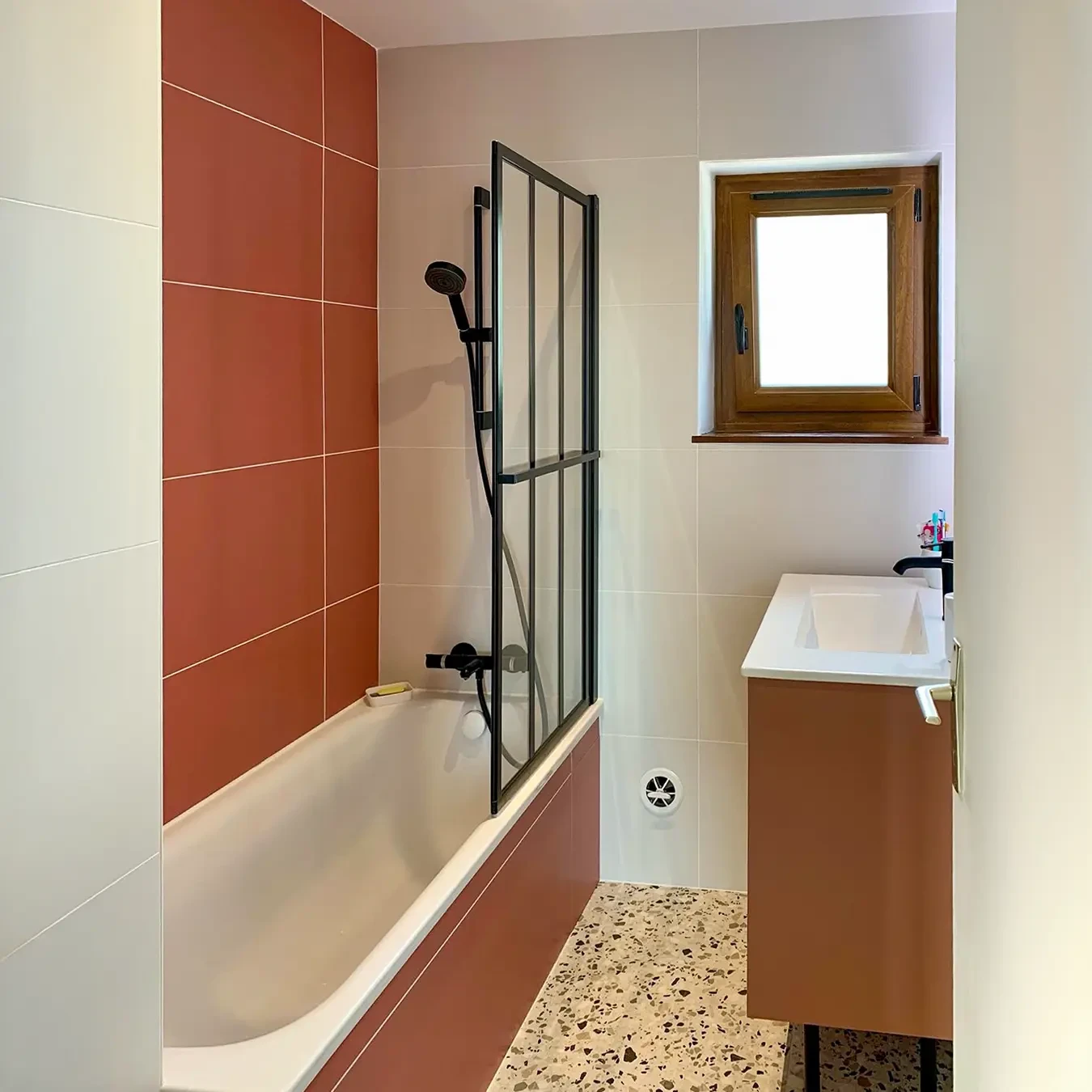 Salle de bain moderne avec douche à l'italienne équipée d'une robinetterie murale chromée, douchette à main et pommeau de douche fixe