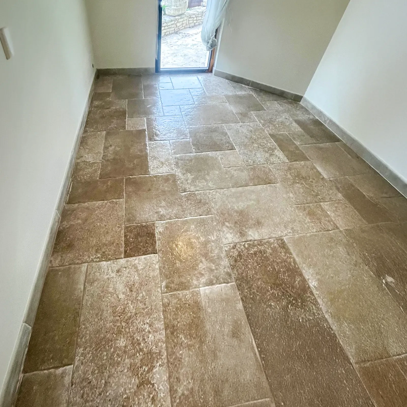 Homme en vêtement de travail traçant une ligne au crayon sur carrelage blanc moucheté, utilisant une règle comme guide