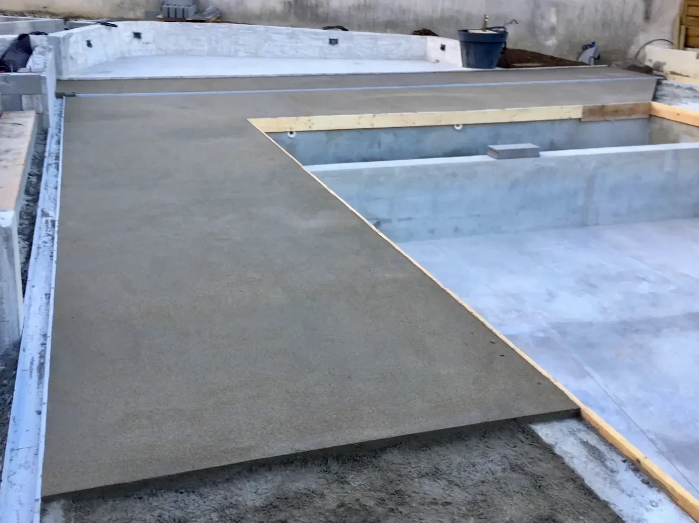 Deux ouvriers en vêtements haute visibilité jaune et orange travaillent sur une surface en béton frais